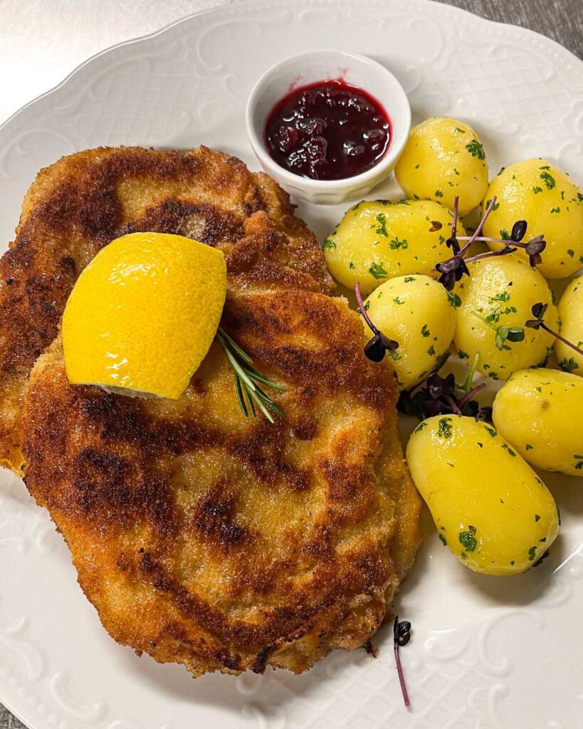 Paniertes Schnitzel mit Kartoffeln, Zitrone und Preiselbeeren im Brauereigasthof Werneck.