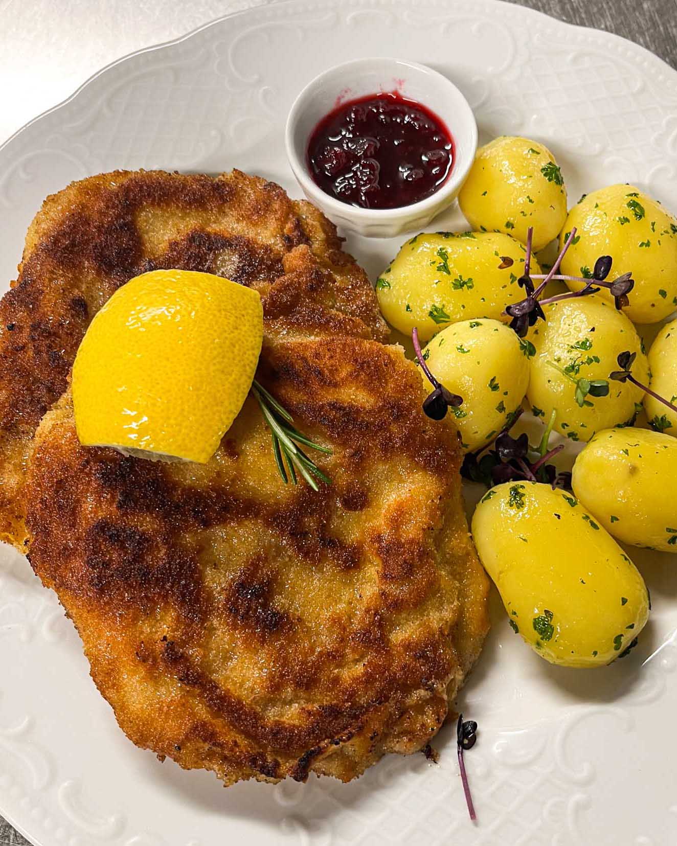 Paniertes Schnitzel mit Kartoffeln, Zitrone und Preiselbeeren im Brauereigasthof Werneck.